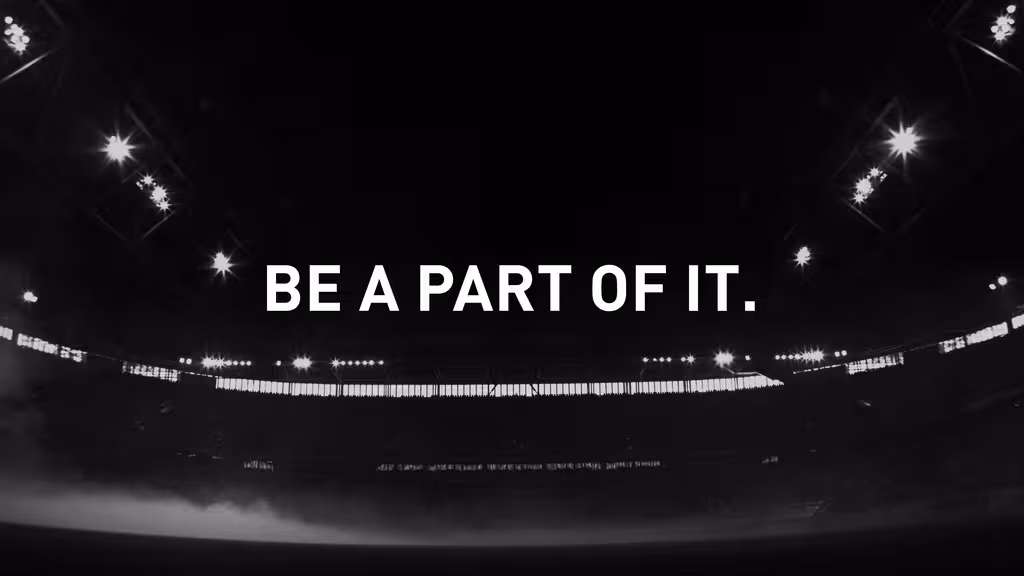 Ein Stadion im Dunkeln, darüber der Text "BE PART OF IT."