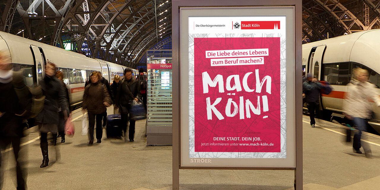 Ein Plakat mit dem Satz "Mach Köln!" am Bahnsteig.