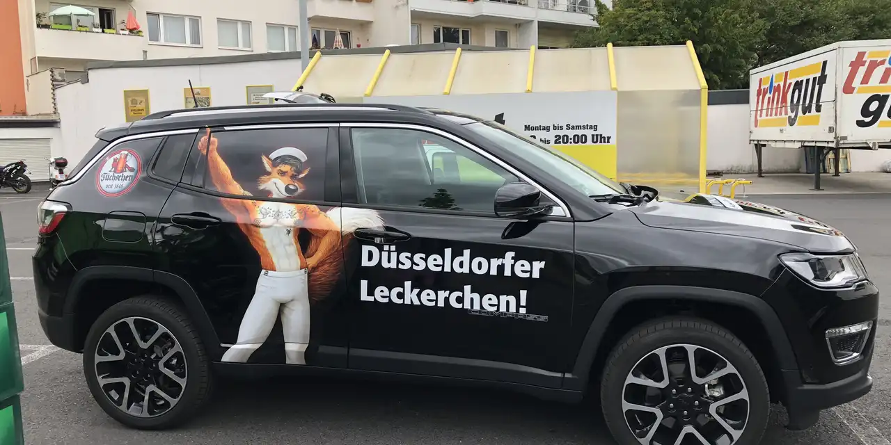 Ein Auto mit einem Werbeschriftzug der Brauerei Füchschen