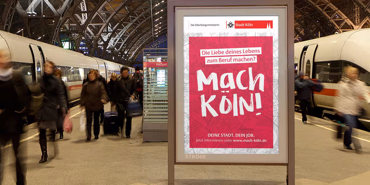 Ein Plakat mit dem Satz "Mach Köln!" am Bahnsteig.