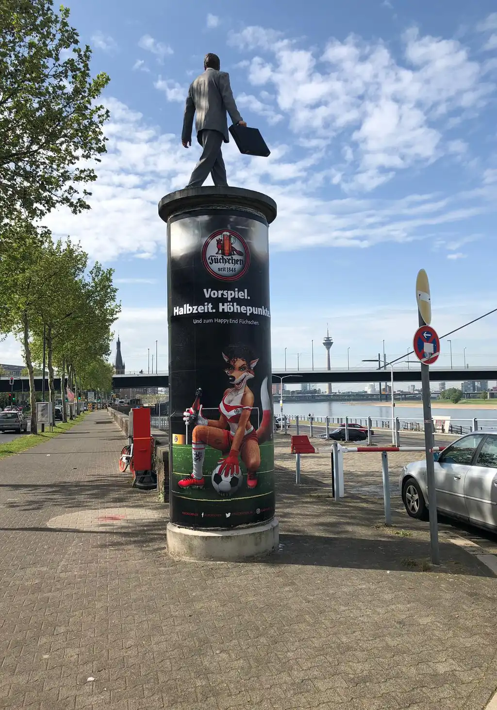 Werbeplakat der Brauerei Füchschen auf einer Litfaßsäule am Rheinufer in Düsseldor