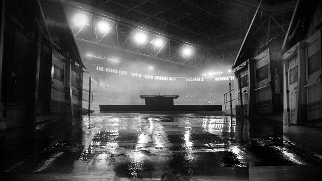 Ein schwarz-weiß Bild, aus dem Eingang in ein beleuchtetes Stadion aufgenommen.