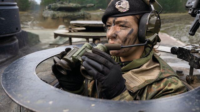 Ein Soldatin mit Kopfhörern, Mikrofon und Fernglas.