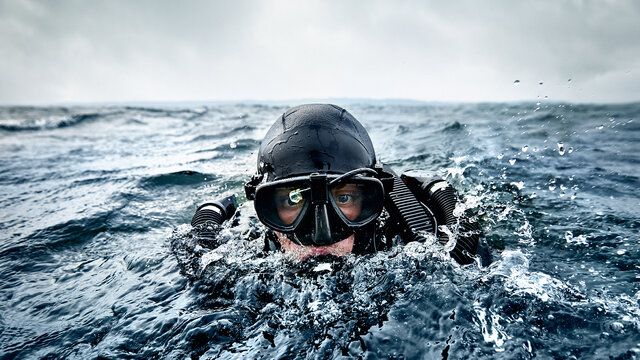 Ein Marine Taucher taucht aus dem Wasser auf