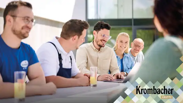 Mitarbeiter von Krombacher sitzen sich an einem Tisch gegenüber.
