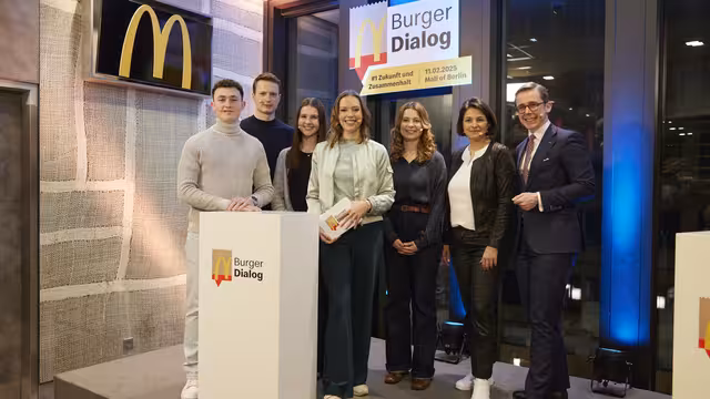 7 Personen, darunter Politiker aller Parteien, stehen unter dem Schild Burger Dialog in einer McDonald´s Filiale.