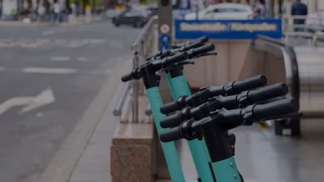 Mehrere Scooter, die vor einer U-Bahn-Haltestelle abgestellt sind.