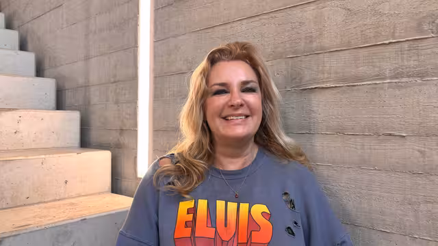 Bettina Nolden, Mitarbeiterin der Castenow GmbH, sitzt im Treppenhaus vor einer Betonwand und lächelt in die Kamera.