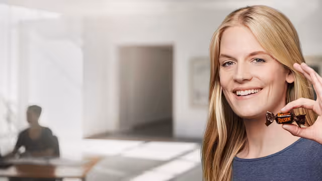 Eine Storck-Mitarbeiterin hält ein Bonbon in die Kamera.