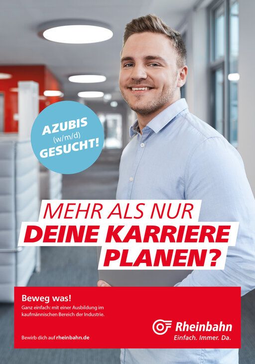 Ein junger Mitarbeiter der Rheinbahn steht im modernen Bürogebäude und lacht in die Kamera.