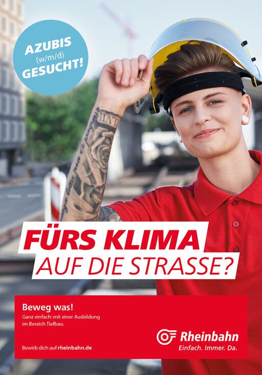 Eine junge Mitarbeiterin der Rheinbahn lacht mit Helm auf dem Kopf in die Kamera.