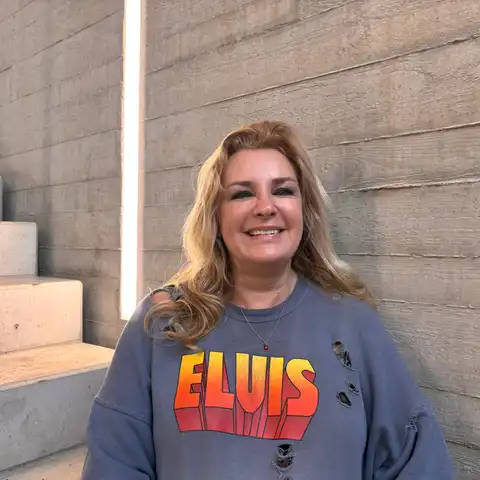 Bettina Nolden, Mitarbeiterin der Castenow GmbH, sitzt im Treppenhaus vor einer Betonwand und lächelt in die Kamera.