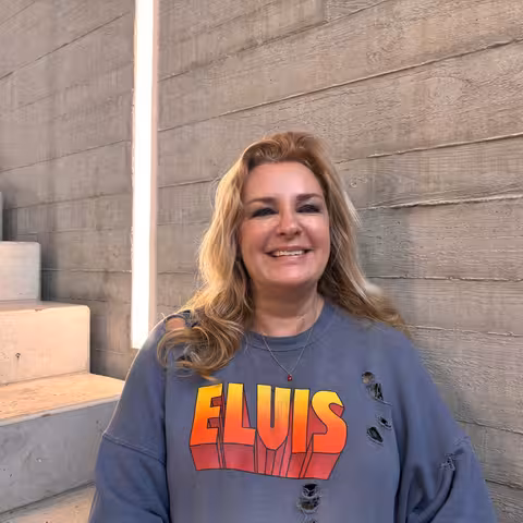 Bettina Nolden, Mitarbeiterin der Castenow GmbH, sitzt im Treppenhaus vor einer Betonwand und lächelt in die Kamera.