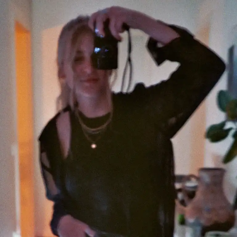 Nadja Ern, Mitarbeiterin der Castenow GmbH, steht im Flur einer Wohnung und fotografiert sich selbst im Spiegel.