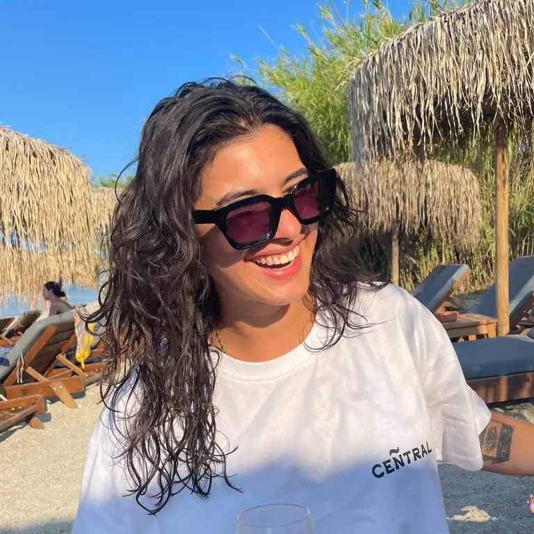 Noa Brammertz - Mitarbeiterin der Castenow Gmbh steht mit Sonnenbrille am Strand.