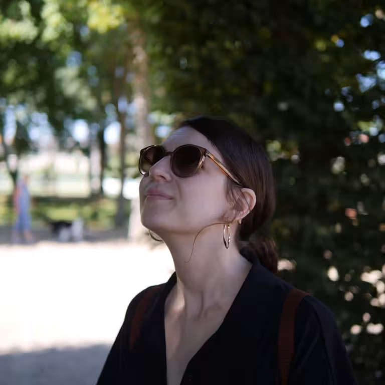 Julia Küpper, Mitarbeiterin der Castenow GmbH, steht im Schatten unter einem Baum. Sie trägt eine Sonnenbrille und ein schwarzes Oberteil.