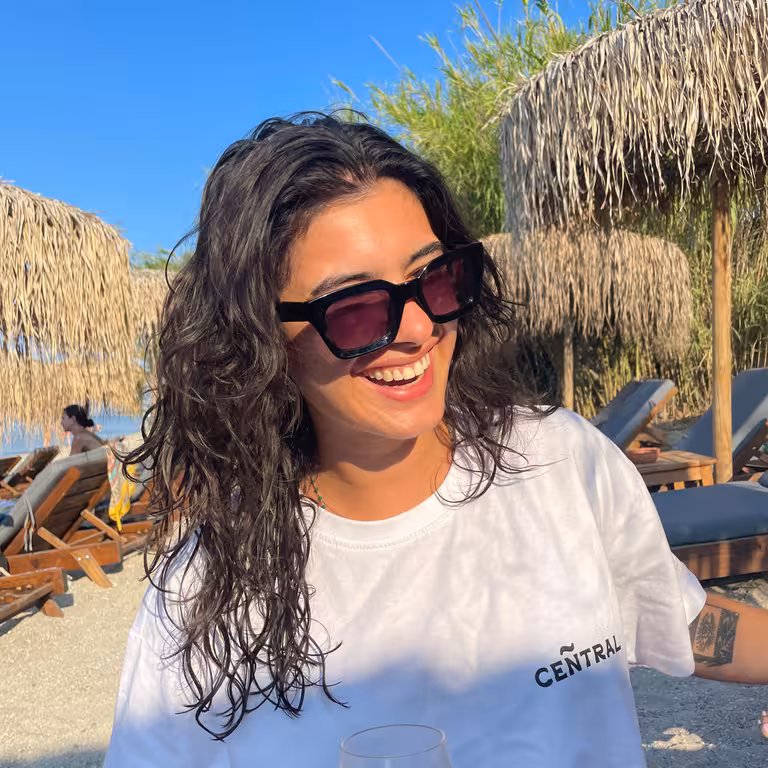 Noa Brammertz - Mitarbeiterin der Castenow Gmbh steht mit Sonnenbrille am Strand.