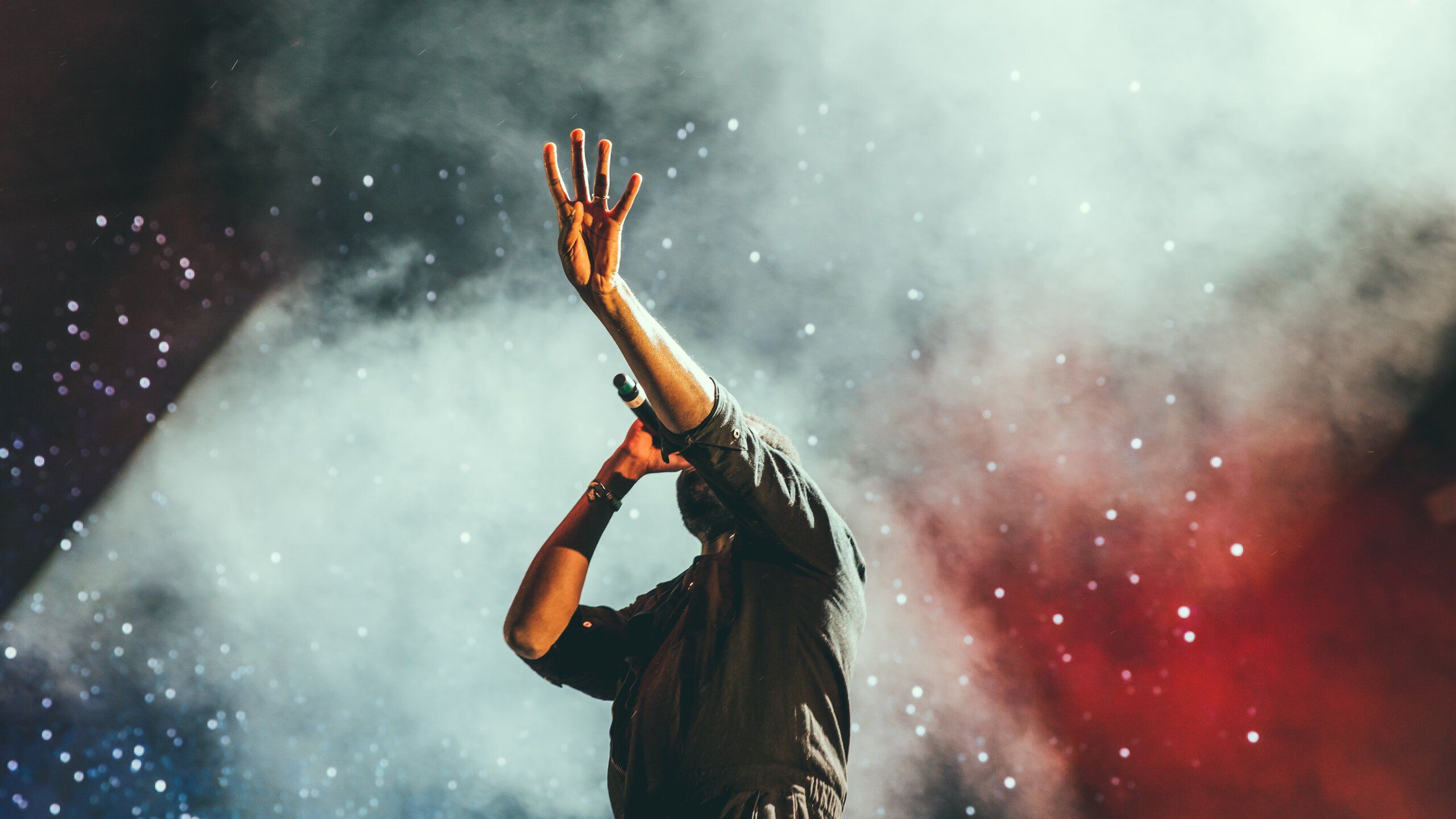 Ein Sänger steht mit ausgestreckter Hand vor eine Nebelwand
