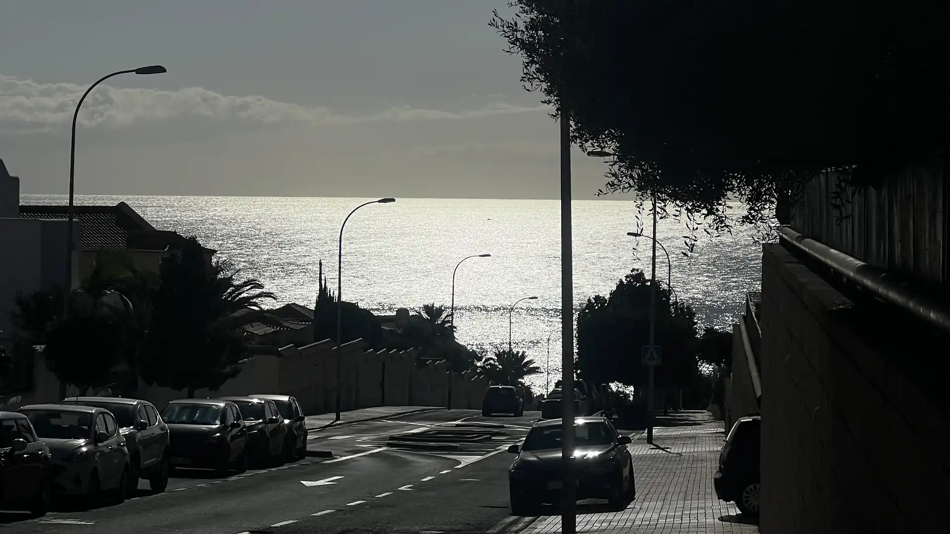Eine Straße im Sonnenlicht, die bergab zum Meer führt.