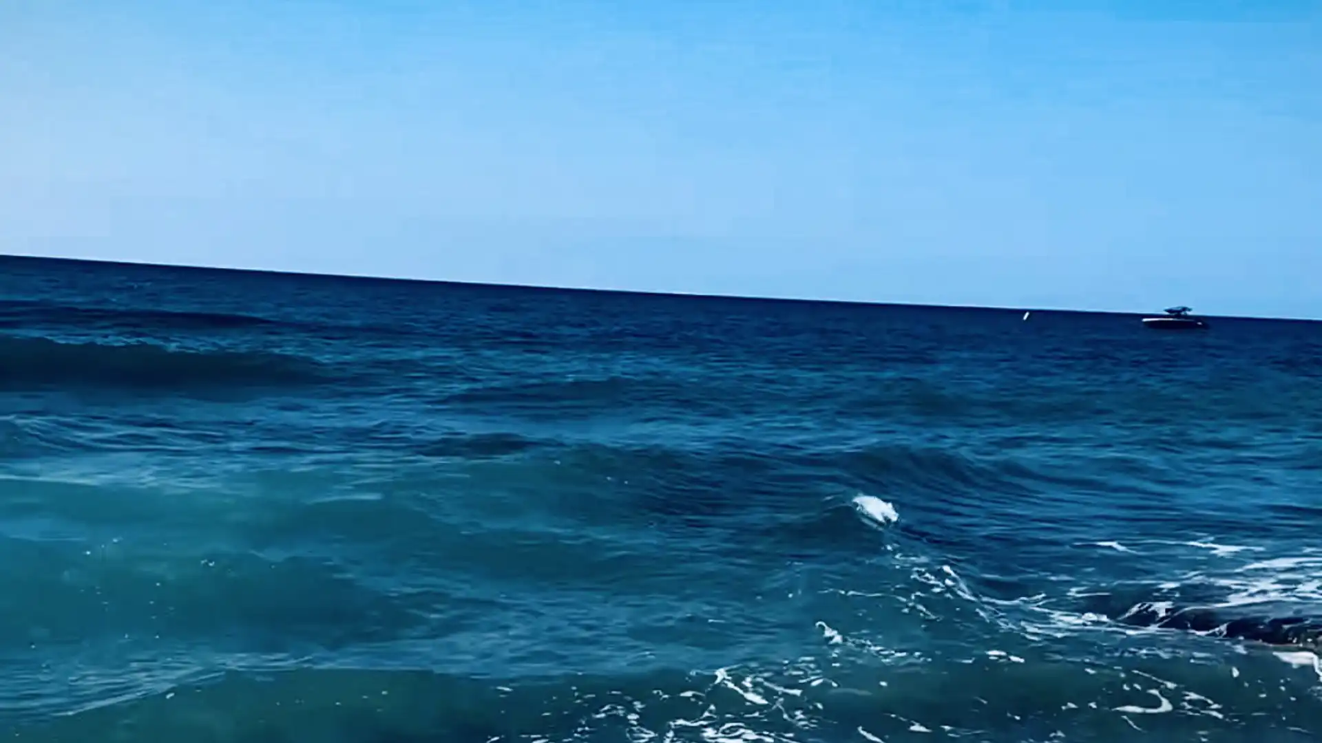 Der Blick über das Meer zum Horizont unter blauem Himmel. 