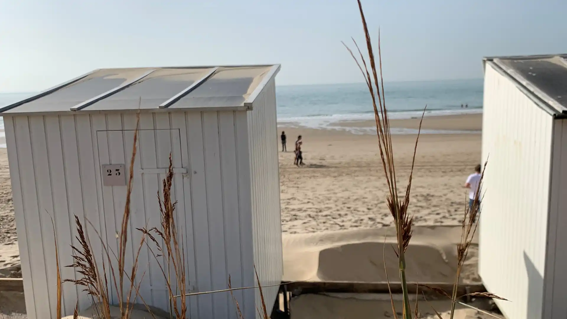 Zwei Hütten am Strand vor blauem Himmel.