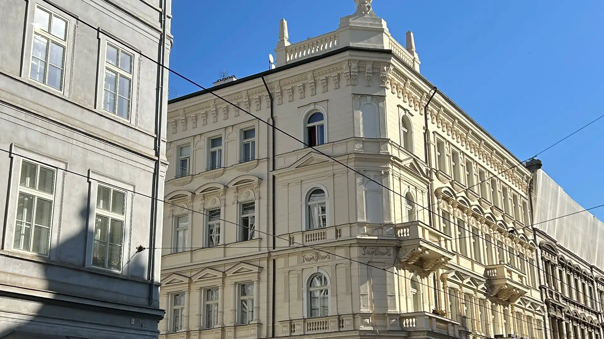 Ein helles Gebäude an einer Straßenecke vor blauem Himmel.