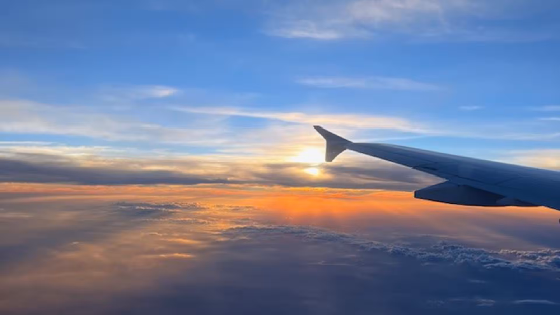 Ein Foto aus dem Flugzeug aufgenommen: die Tragflächen sind vor einem Sonnenuntergang zu sehen.