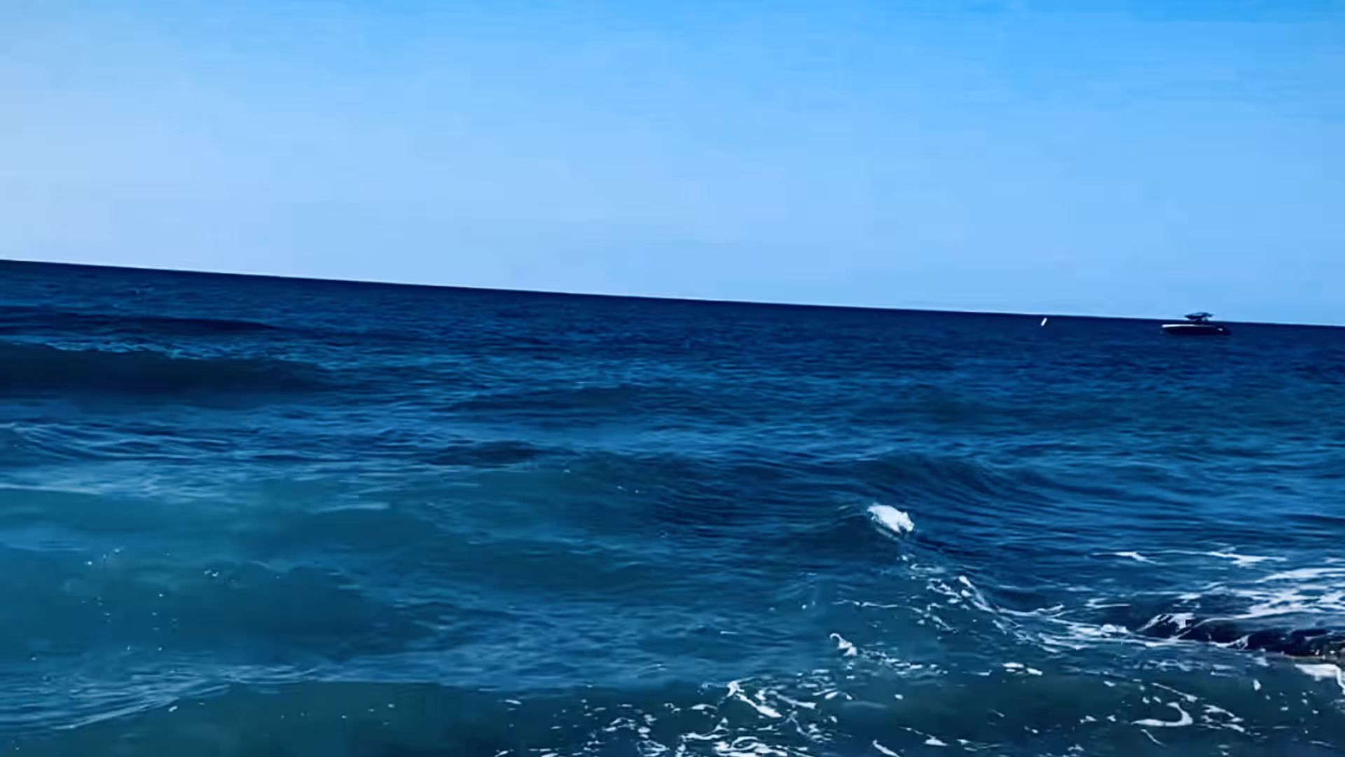 Der Blick über das Meer zum Horizont unter blauem Himmel. 