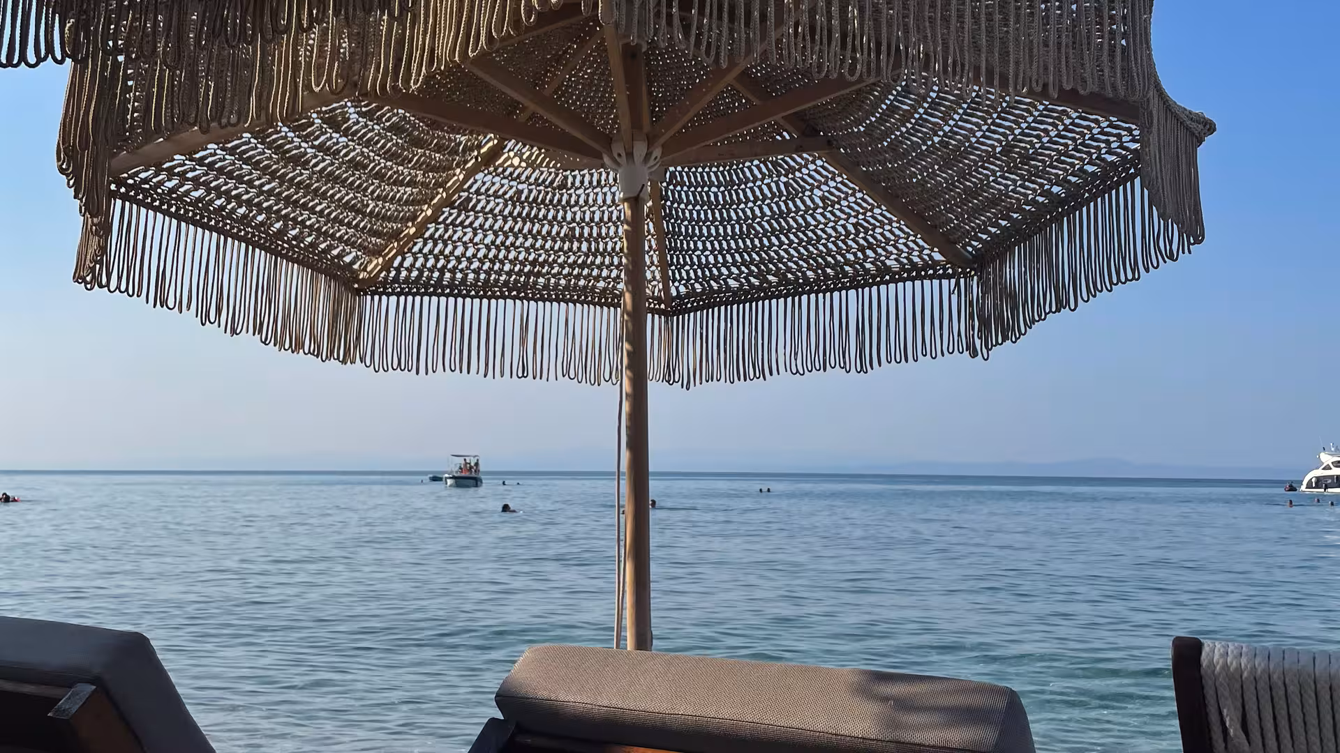 Ein Sonnenschirm und eine Sonnenliege am Strand vor einem blauen Himmel