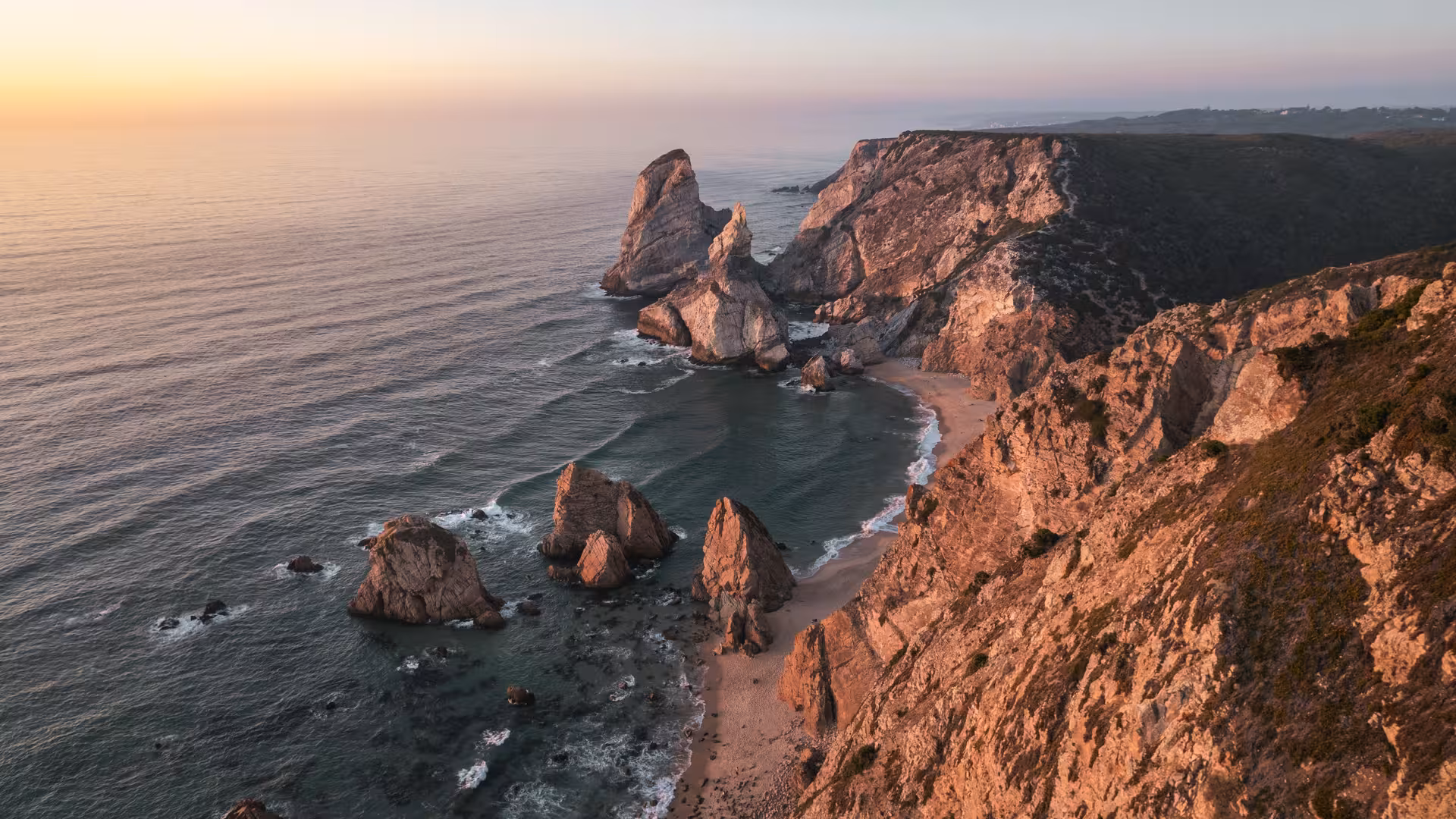 Die schroffe Küste am Meer, die von der untergehenden Sonne beschienen wird.