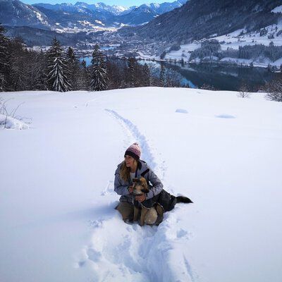 Kathrin Lenzer, Mitarbeiterin der Castenow GmbH, sitzt mit ihrem Hund im Schnee.