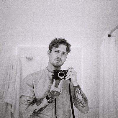Jannis Mattar, Texter bei der Castenow GmbH, erstellt ein Foto mit einem Fotoapparat vor dem Spiegel eines Badezimmers.