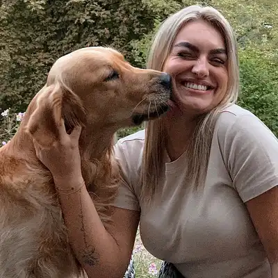 Cara Remscheid, Mitarbeiterin der Castenow GmbH, wird von einem Hund auf die Wange geküsst.