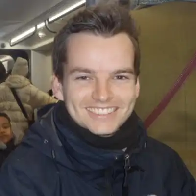 Johannes Hinkel, Mitarbeiter der Castenow GmbH, sitz in einer vollbesetzten U-Bahn und lacht in die Kamera.