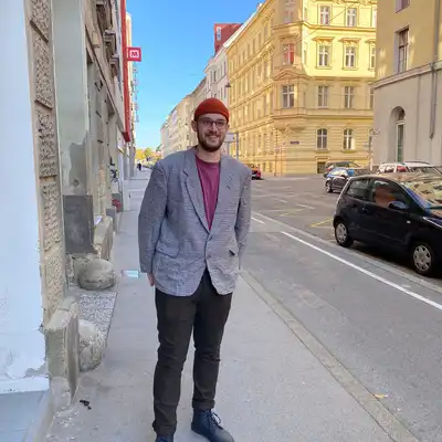 Robin Uebber, Mitarbeiter der Castenow GmbH, auf dem Bürgersteig vor hohen Häusern in der Stadt.