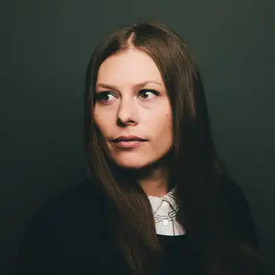 Katharina Marker, Mitarbeiter in der Castenow GmbH, hat lange braune Haare mit einem Scheitel in der Mitte.