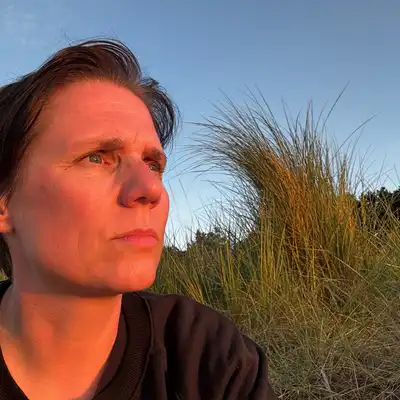 Martit Gottschlich, Mitarbeiterin der Castenow GmbH, sitzt am Meer, die untergehende Sonne erhellt ihr Gesicht.
