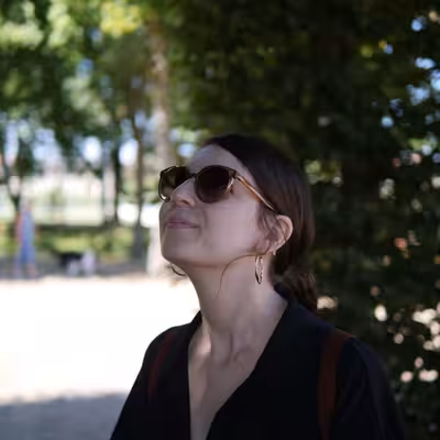 Julia Küpper, Mitarbeiterin der Castenow GmbH, steht im Schatten unter einem Baum. Sie trägt eine Sonnenbrille und ein schwarzes Oberteil.