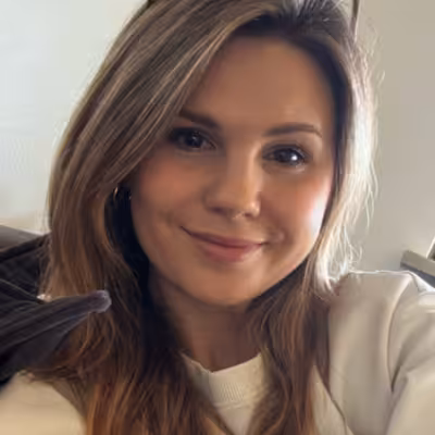 Nicole Schuler, Mitarbeiterin der Castenow GmbH in München, trägt einen weißen Pullover und die Sonnenbrille im Haar.