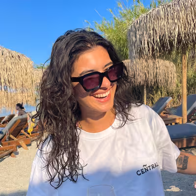 Noa Brammertz - Mitarbeiterin der Castenow Gmbh steht mit Sonnenbrille am Strand.