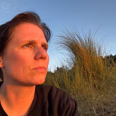 Martit Gottschlich, Mitarbeiterin der Castenow GmbH, sitzt am Meer, die untergehende Sonne erhellt ihr Gesicht.